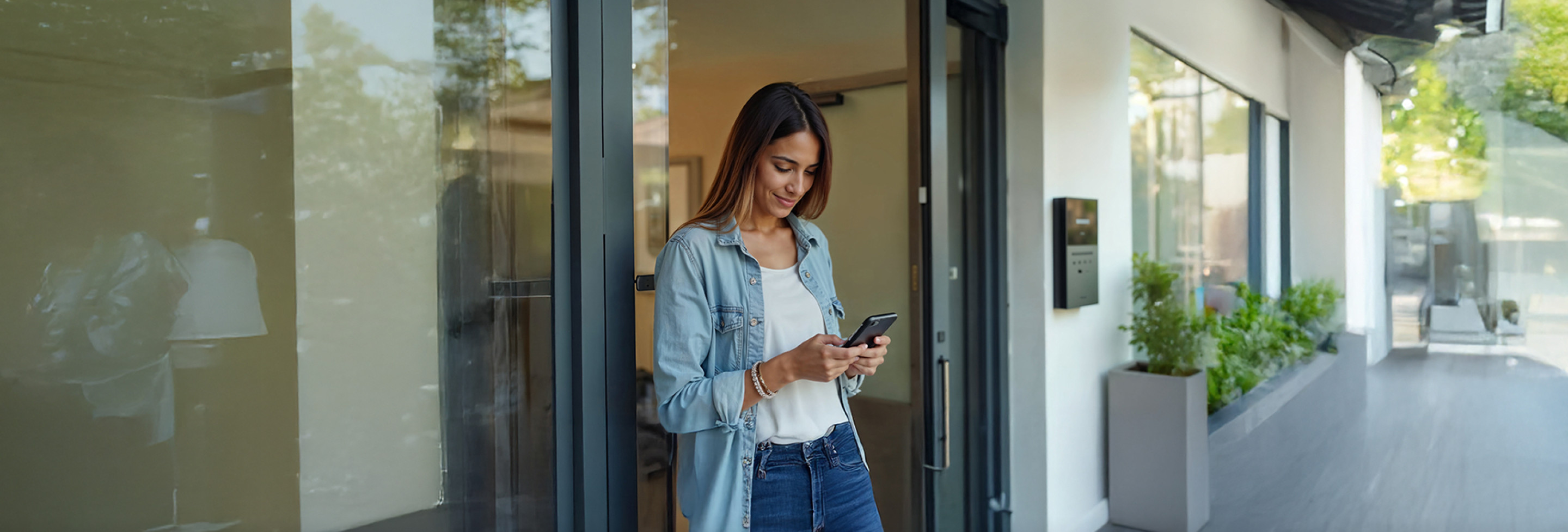 Mujer sonriente revisando su celular al salir de una oficina moderna, representa el dinamismo, confianza y accesibilidad de BIT Technologies.